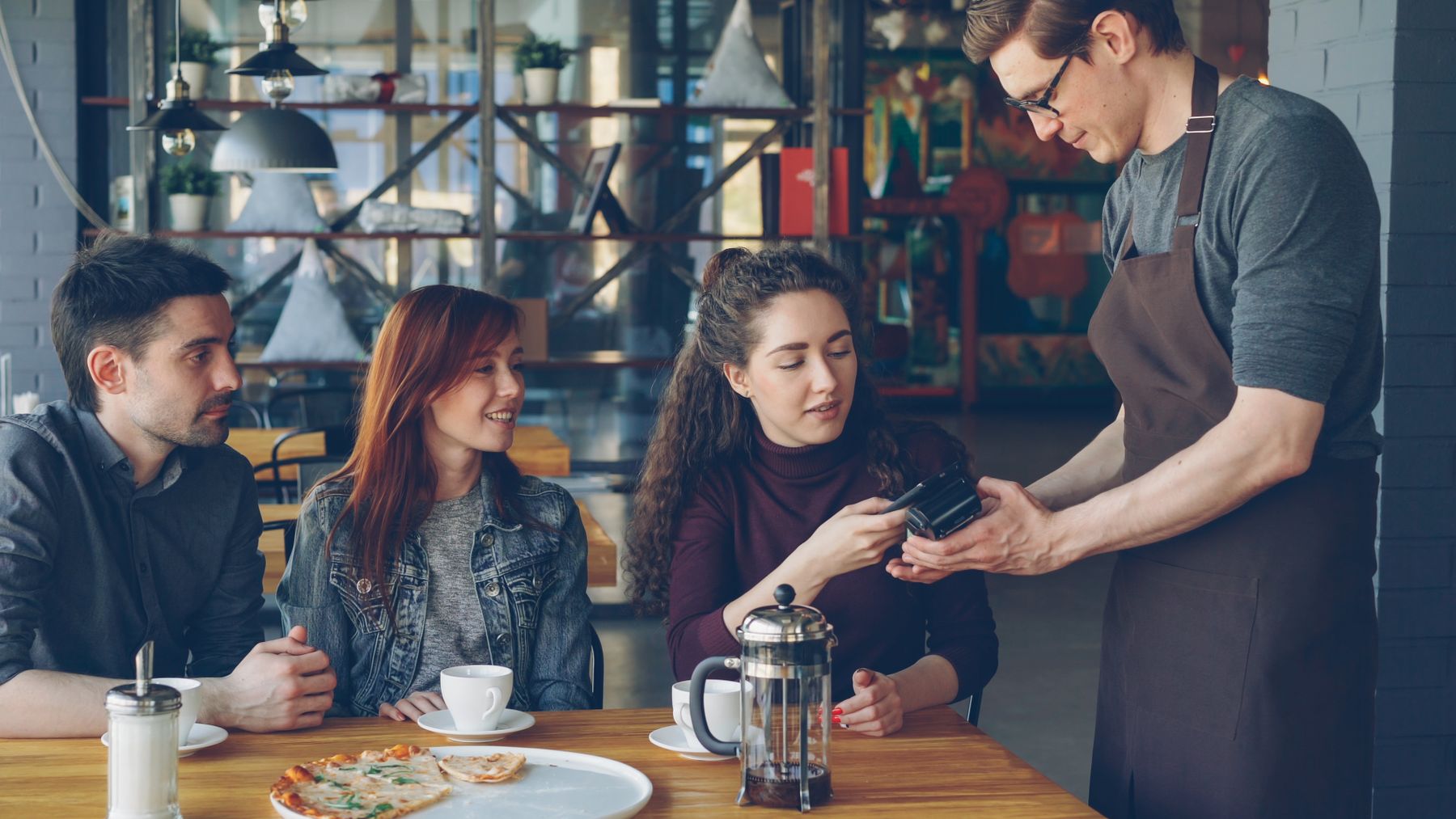 Friends paying for a meal together at a café