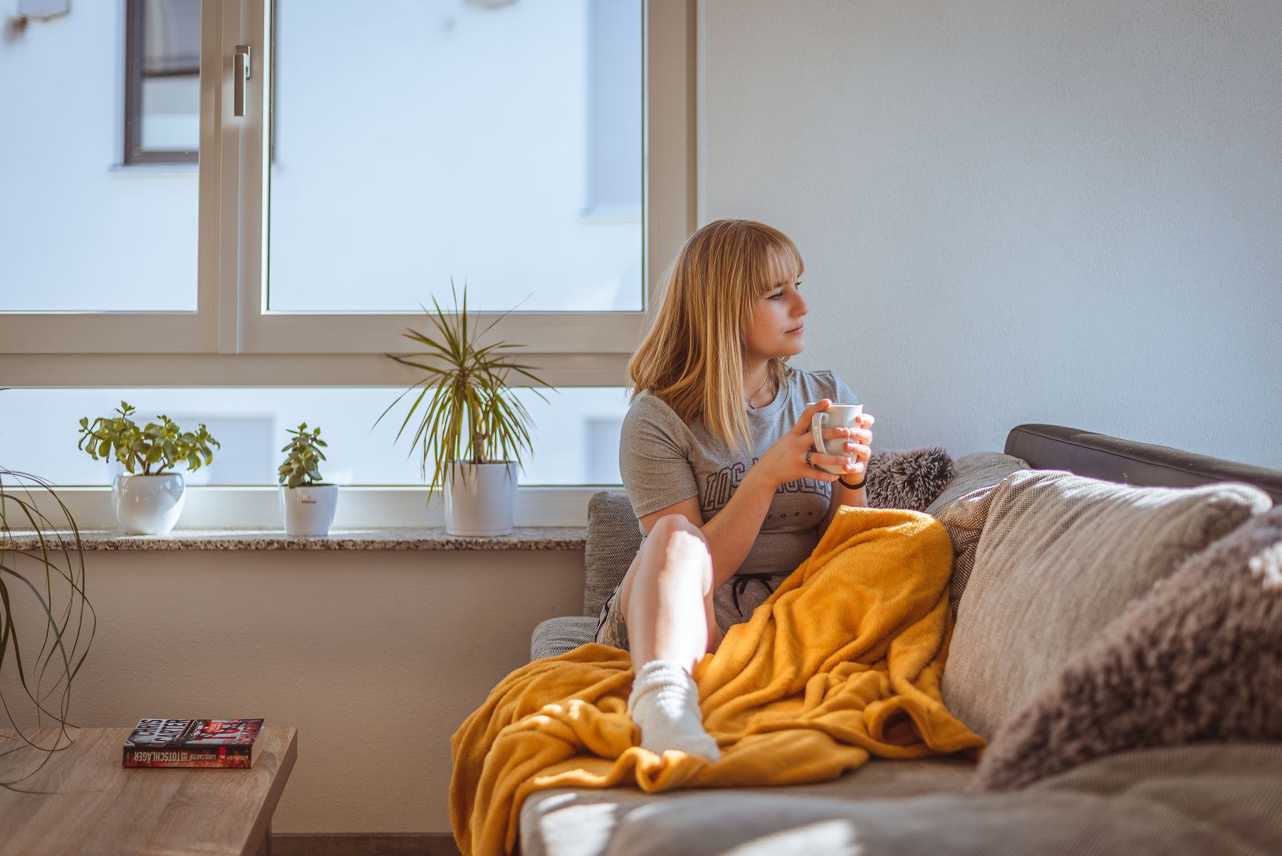 A quiet moment with coffee and a blanket on a sunlit sofa